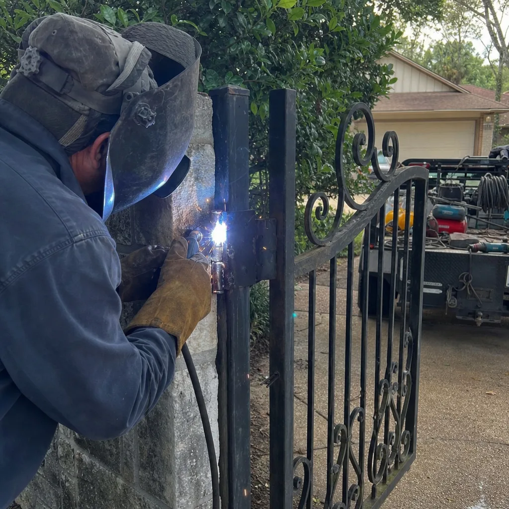 Professional welding and repair service on a decorative metal gate hinge.